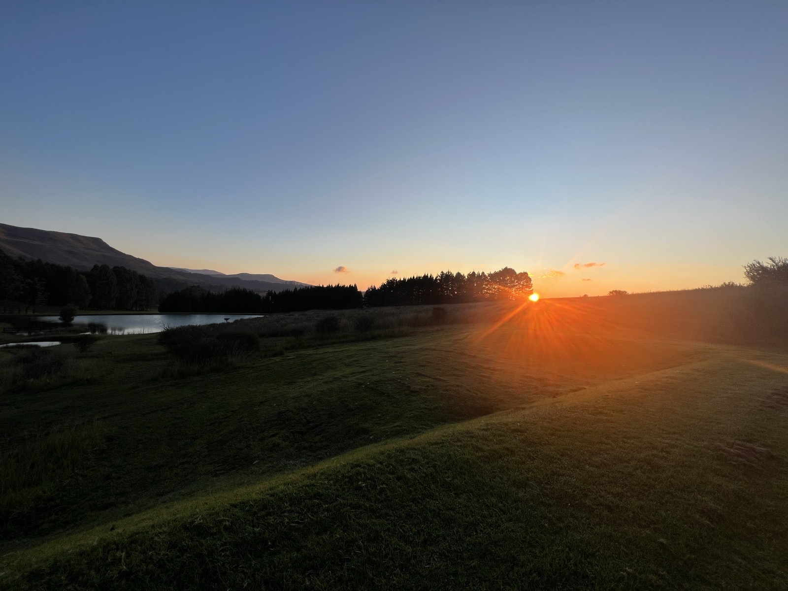 Sunrise over the dam with mountains and starburst light